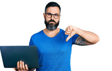 Hispanic man with beard working using computer laptop with angry face, negative sign showing...