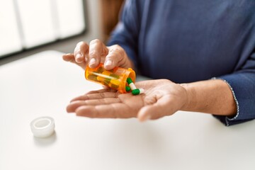 Woman taking pills sitting on the table at home.