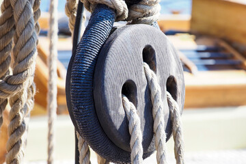 Part of an old sailing wooden ship with pulleys, knotted ropes and wooden fasteners. Rigging on an...