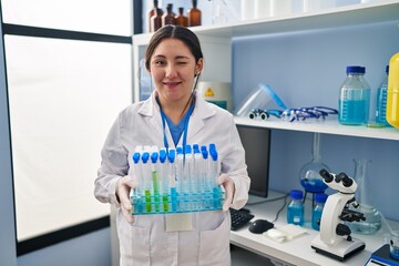 Young latin woman working at scientist laboratory winking looking at the camera with sexy...
