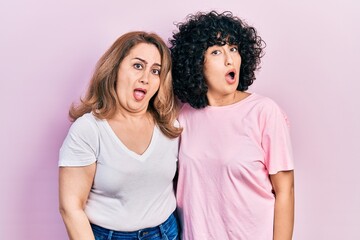 Fototapeta premium Middle east mother and daughter wearing casual clothes in shock face, looking skeptical and sarcastic, surprised with open mouth