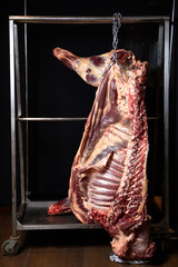 beef carcass hanging on a black background
