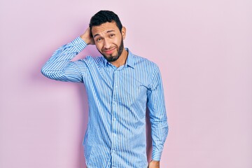 Hispanic man with beard wearing casual blue shirt confuse and wonder about question. uncertain with...