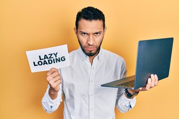 Hispanic man with beard working using computer laptop holding lazy loading banner skeptic and nervous, frowning upset because of problem. negative person.