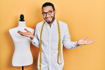 Hispanic man with beard dressmaker designer standing by manikin clueless and confused expression...