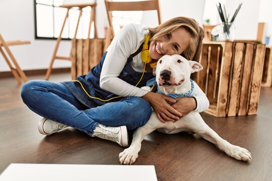 Young caucasian woman smiling confident hugging dog at art studio