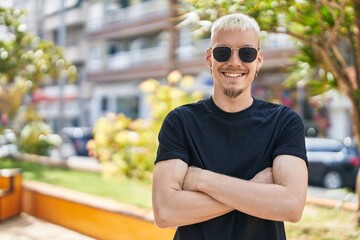 Young caucasian man smiling confident standing with arms crossed gesture at park