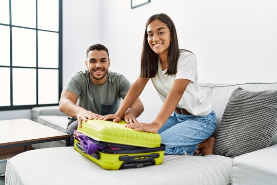 Latin man and woman couple smiling confident close travel suitcase at home