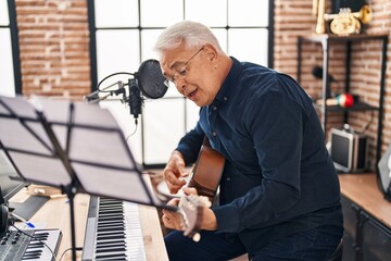 Senior man musician playing guitar at music studio