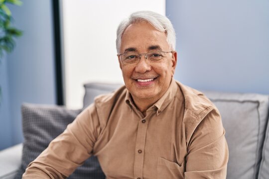 Senior man smiling confident sitting on sofa at home