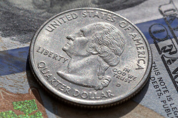 quarter dollar coin lying on one hundred dollars banknote