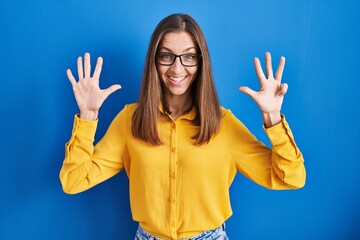 Young woman wearing glasses standing over blue background showing and pointing up with fingers...
