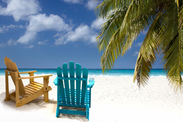 Two wooden beach chairs under palm branch on Caribbean coast