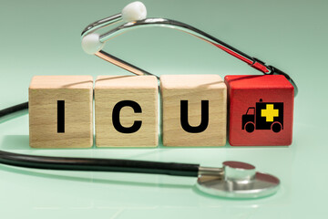 Medical stethoscope, wooden blocks with the words ICU intensive care unit, symbol of an ambulance,...