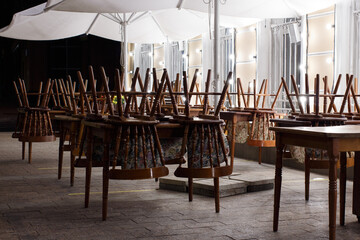 Closed summer cafe at night in the city, the chairs are turned over on the tables.