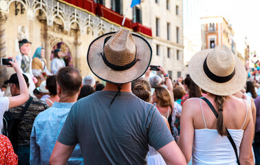 tourists and people from Alicante watching and recording with their mobile phones the parades and dances in the festivities of the bonfires of Alicante, the giants in the background.

