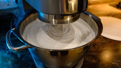 Beaten egg cream whites until frothy. Whipped egg whites for a meringue. Red stationary mixer, food processor take out beater