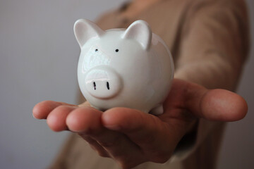 Man hand holding piggy bank in low light, savings and invest for future growth.