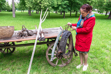 A woman inspects an old horse harness at a village festival. Retro equipment for the carriage of...