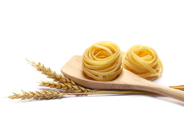 Raw tagliatelle pasta, ears wheat and wooden spoon isolated on white 