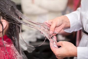 Hairdresser stylist takes care of girl's hair. Hair care procedures in a beauty salon. Hair...