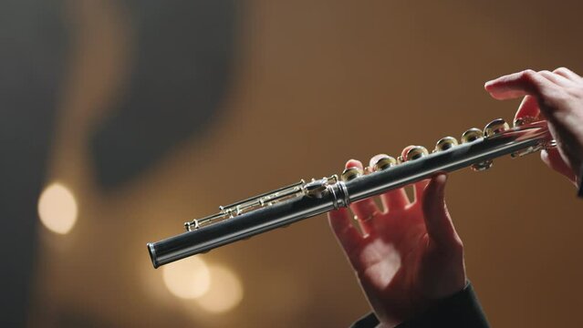 symphonic orchestra concert, closeup of flute in hands of flutist, old opera house or modern music hall