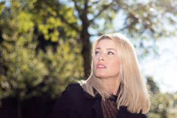 blonde woman looking up pensive in a park