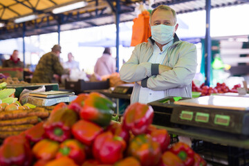 Man in mask buying pepper in market