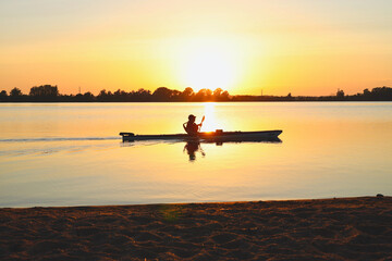 Person kayaking on a lake at sunset