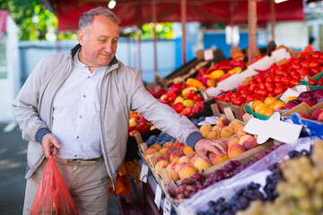Man choosing peaches in market
