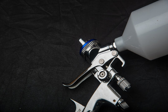 Image of the painter's arm hand holding industrial size spray gun used for industrial painting and coating and isolated on black background