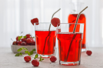 Red refreshing drink with mint on a gray background. A colorful summer non - alcoholic refreshing drink made from berries .