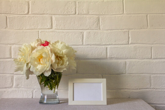 Blank photo frame mockup and peonies bouquet on the table.Copy space.