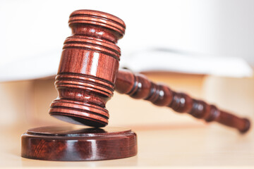 Open law book with a wooden judges gavel on table in a courtroom or law enforcement office