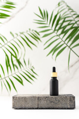 Concrete black podium for cosmetic products close-up among tropical leaves on the background of a...