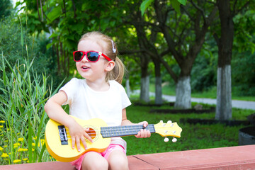 Beautiful girl child summer house lawn with guitar