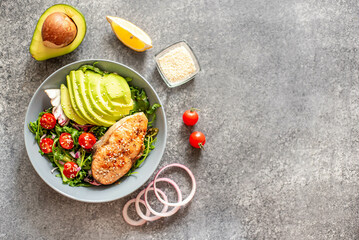 Fototapeta na wymiar grilled salmon steak and fresh green vegetable tomato salad with lettuce and avocado on stone background with copy space for your text