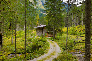 Hiking trail in the Karwendel mountains in Eng, Austria. Middle in the forest there is a house between the trees.