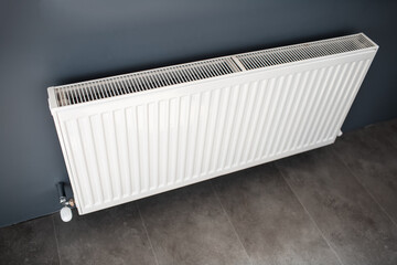 Steel heating radiator of white on a grey wall. Top view.