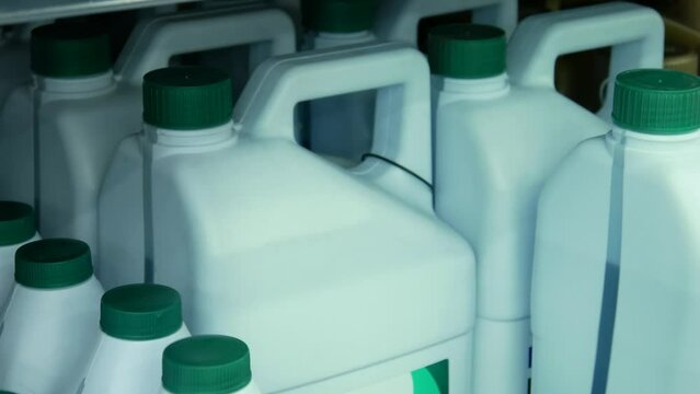 Close-up of many plastic cans of antifreeze and a male buyer's hand takes one