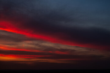 Beautiful landscape of sunset with dark colourful clouds. Natural background.