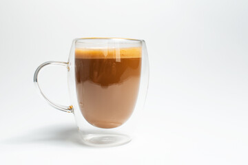 Double walled glass mug with coffee and vegan milk on white, close-up view.
