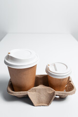 Cardboard holder with paper cups of coffee takeaway on white table.