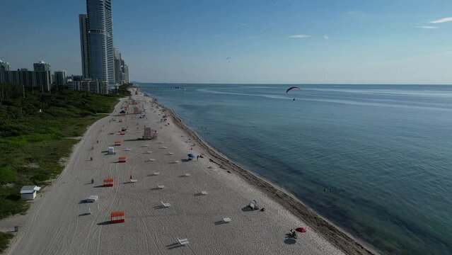 Aerial view of 3 powered parachutes or powered paragliders flying over the beach early in the morning