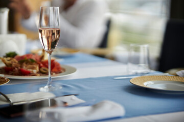 a glass of champagne on a served table, close-up, selective focus. Festive table setting