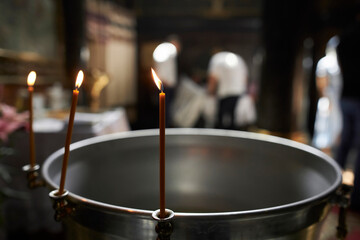 candles near the bowl at the christening of a child in the temple, close-up. Church candles,...