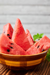 Sliced watermelon decorated with mint leaves on wooden background. Close-up, selective focus