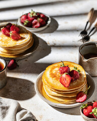 Pancakes with strawberry and honey with striped shadows in hard light cozy rustic composition. Sunny morning breakfast concept