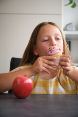 the girl chooses between a cupcake and an apple