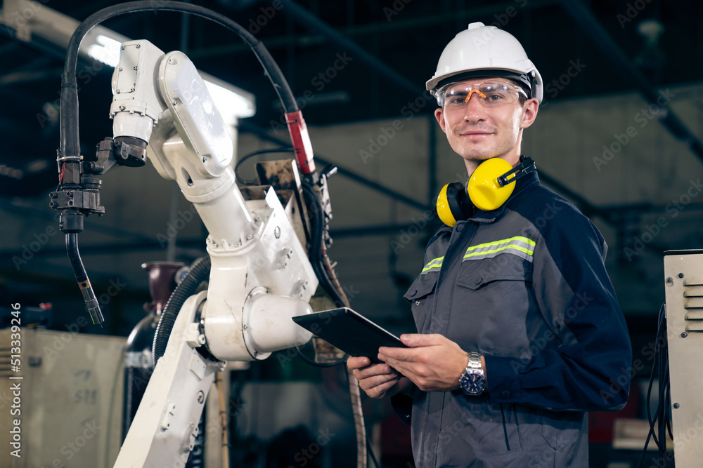 Poster young factory worker working with adept robotic arm in a workshop . industry robot programming softw